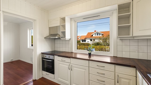 Kjøkkenet ligger i eget rom og har kjøkkeninnredning med profilerte fronter og laminert benkeplate. Det er fliser mellom overskap og benkeplate.