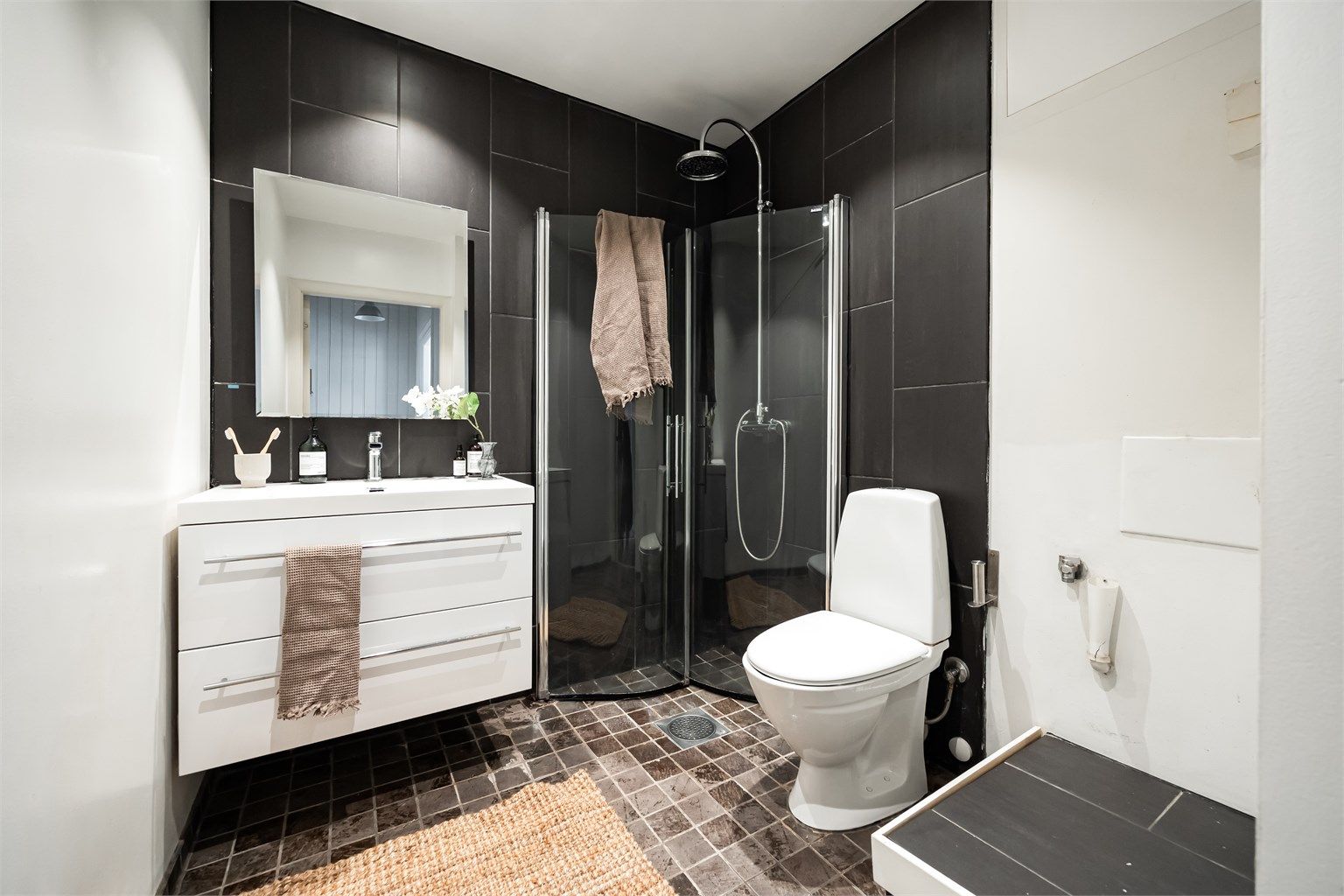 Pent flislagt bad fra 2007 med elektrisk gulvvarme for en behagelig start på dagen. Innredet med gulvstående toalett, servant, speil på vegg og dusjhjørne med buede dører. Det er opplegg for vaskemaskin.