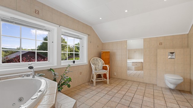 Badet byr på både dusjnisje med glassdører og dusjarmatur samt et innfliset boblebad med dusjarmatur