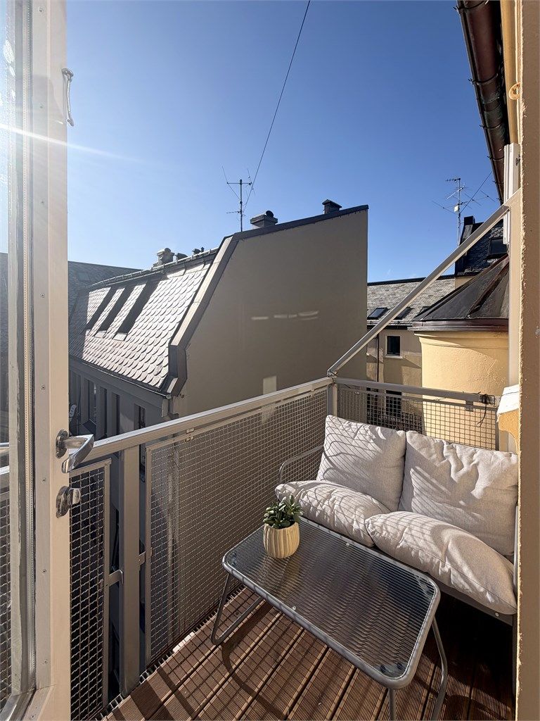 Balkongen vender mot en skjermet bakgård og har plass til en sittegruppe.
