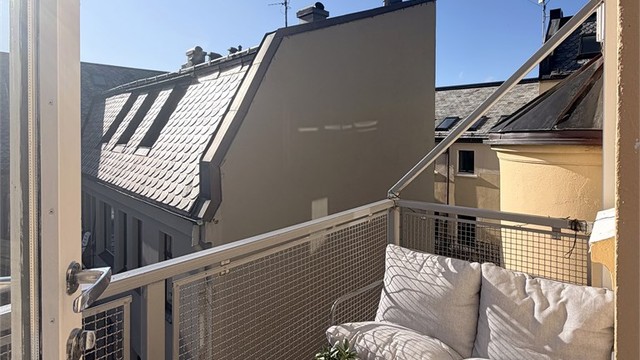 Balkongen vender mot en skjermet bakgård og har plass til en sittegruppe.