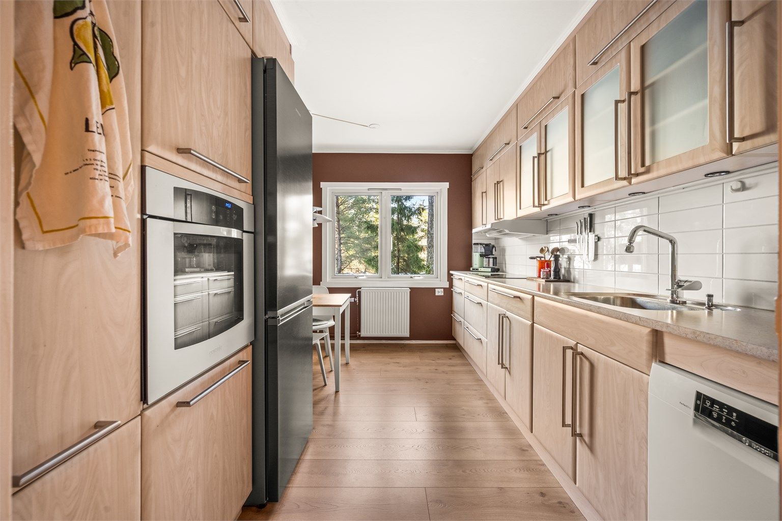 Kjøkkeninnredningen har glatte fronter og en slitesterk laminert benkeplate.