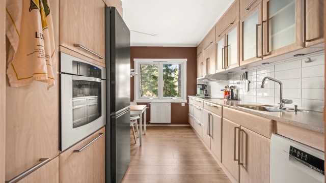 Kjøkkeninnredningen har glatte fronter og en slitesterk laminert benkeplate.