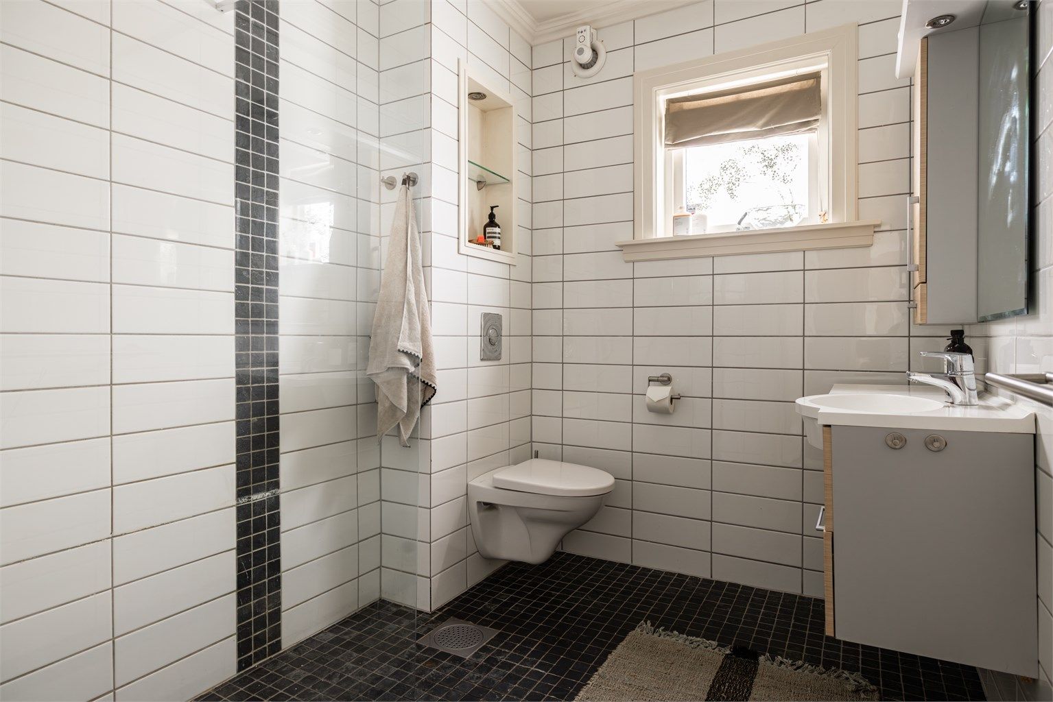 Fullverdig bad med inngang fra gangen i 1. etasje. Rommet ble pusset opp i 2005 og er utstyrt med vegghengt toalett, dusjhjørne med fast glassvegg og servant med underskap