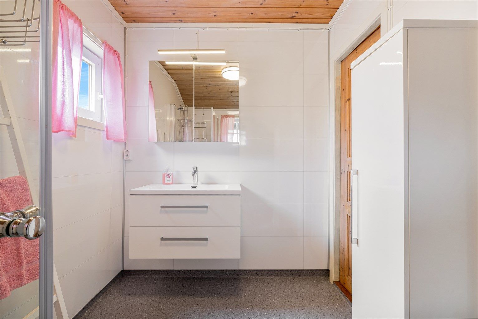 Gulvflatene på badet er belagt med gulvbelegg, på veggene er det baderomsplater og i taket er det panelbord