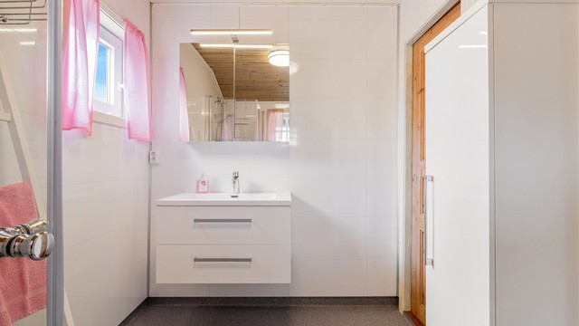 Gulvflatene på badet er belagt med gulvbelegg, på veggene er det baderomsplater og i taket er det panelbord