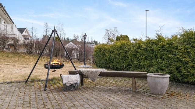 Uteområdet er pent opparbeidet med en romslig gårdsplass belagt med belegningsstein, fine plenarealer og hekker rundt eiendommen.