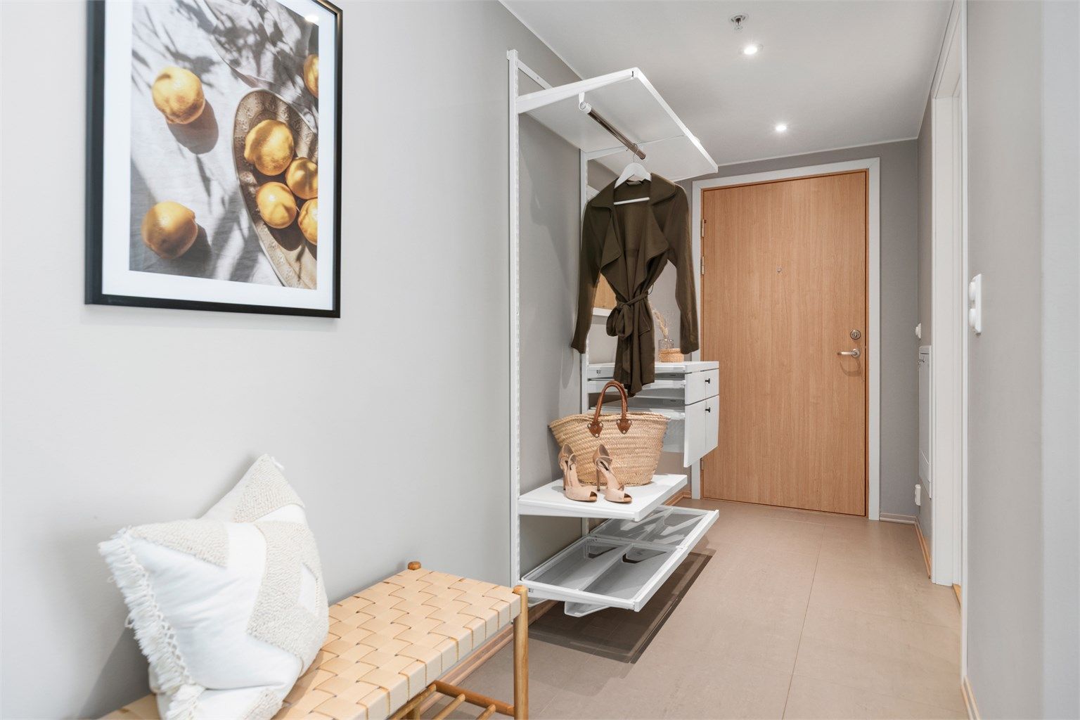 Man kommer inn i en lys entré med flislagt gulv, vannbåren varme og downlights i himling.
