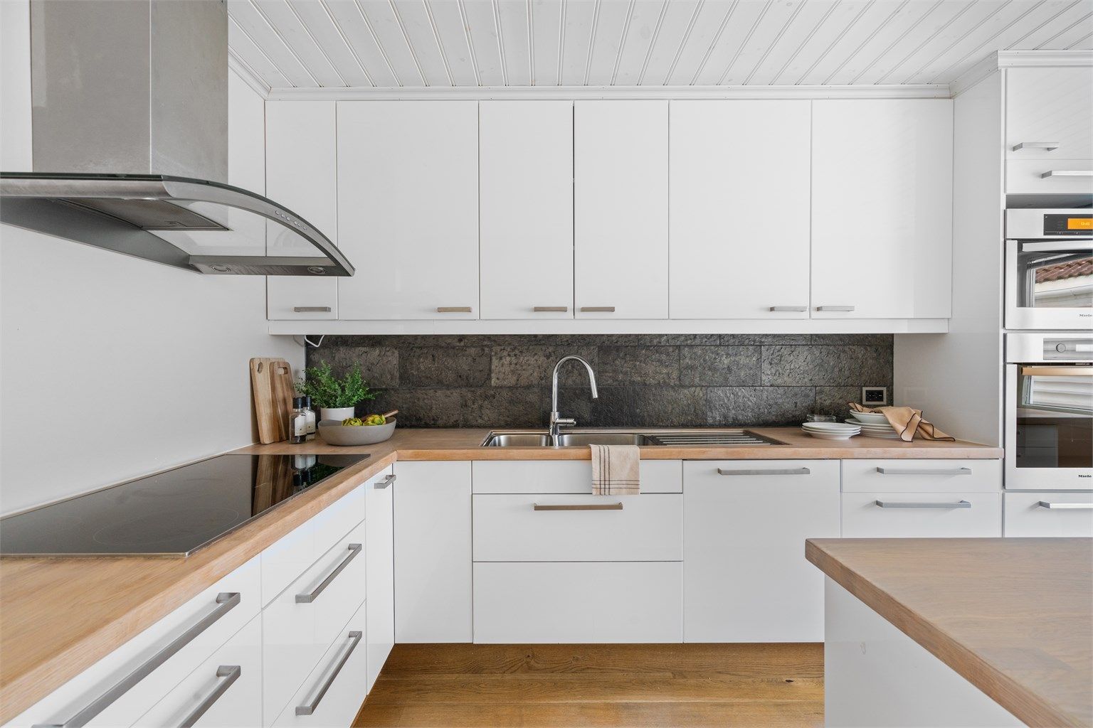 Fliser på vegg mellom overskap og benk.
Enstavsparkett på gulv.  Et meget kjekt rom.