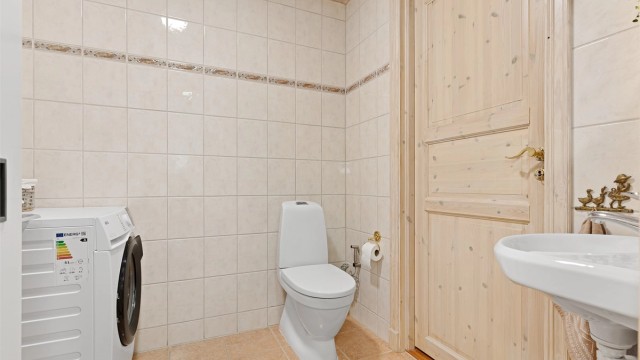 Første etasje inneholder også et praktisk vaskerom med toalett. Innenfor vaskerommet er det en god bod med varmtvannsbereder