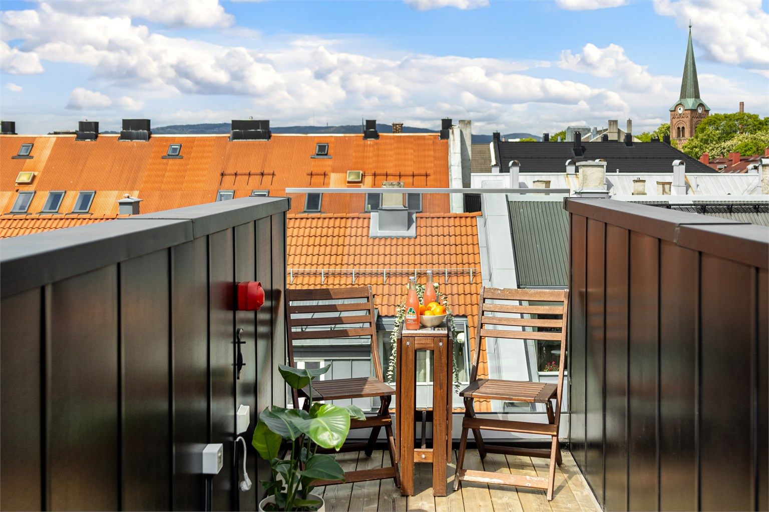 Terrassen har gulv av terrassebord og glassrekkverk.