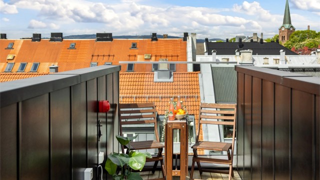 Terrassen har gulv av terrassebord og glassrekkverk.