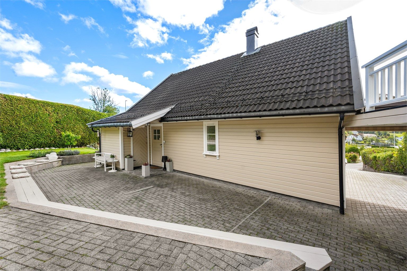 Gårdsplassen er belagt med belegningsstein og gir enkel adkomst til inngangspartiet og carporten.