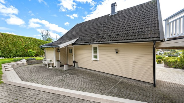 Gårdsplassen er belagt med belegningsstein og gir enkel adkomst til inngangspartiet og carporten.