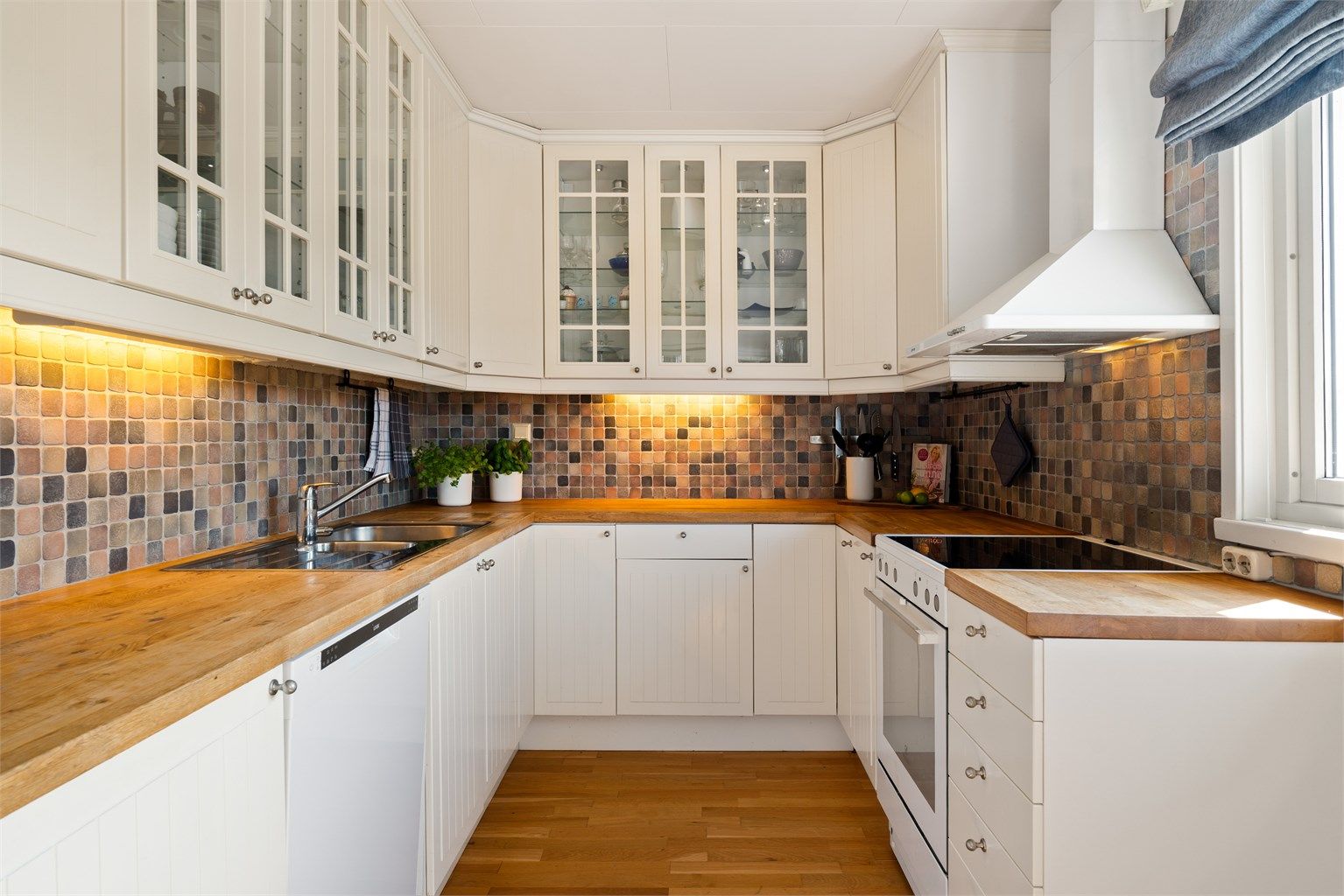 Kjøkkenet ligger naturlig tilbaketrukket fra stuen og er innredet med lyse slette fronter og benkeplate av tre.