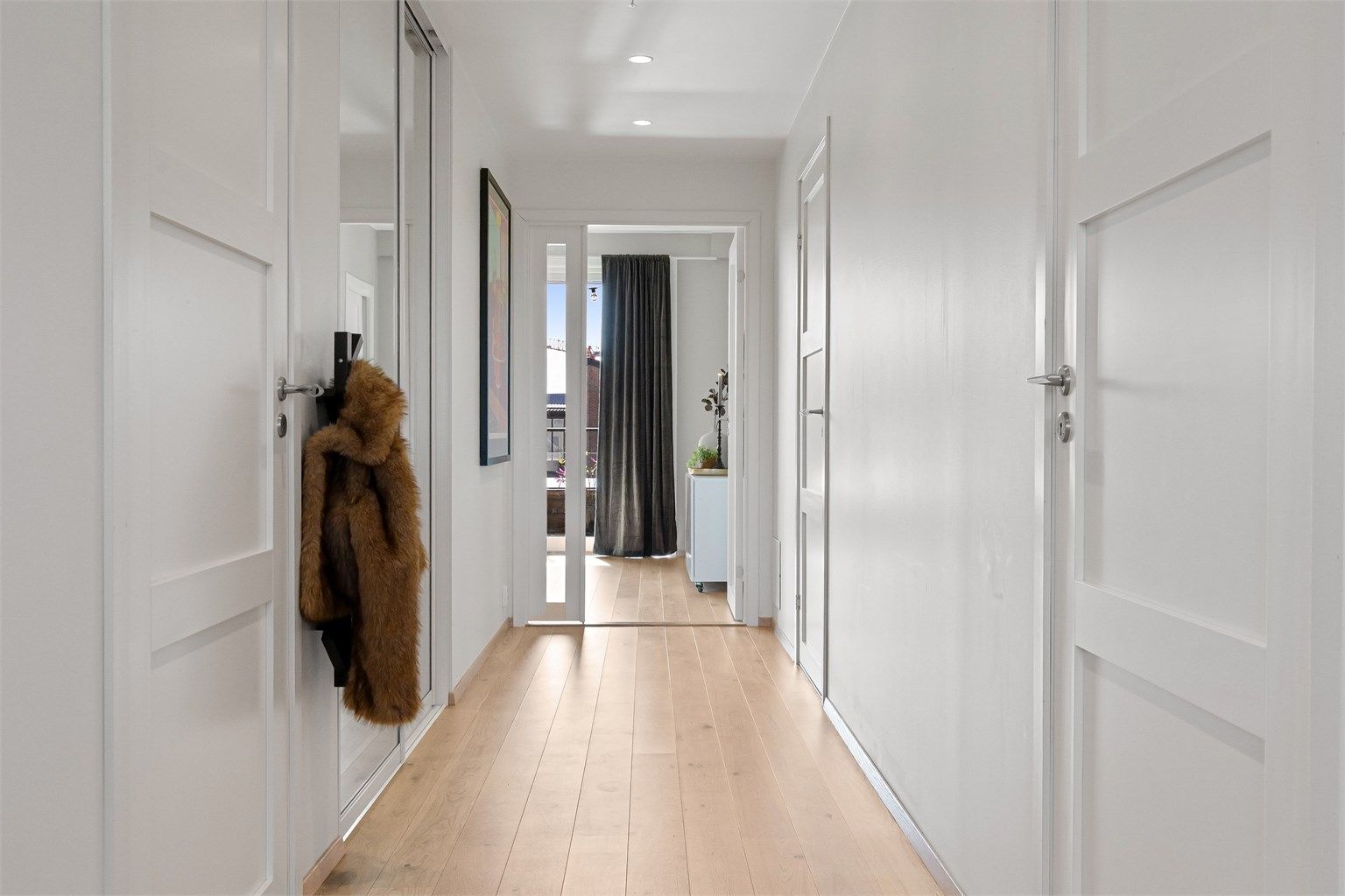 En skyvedørsgarderobe med speilfronter i gangen gir gode oppbevaringsmuligheter for yttertøy.
