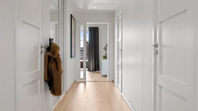 En skyvedørsgarderobe med speilfronter i gangen gir gode oppbevaringsmuligheter for yttertøy.