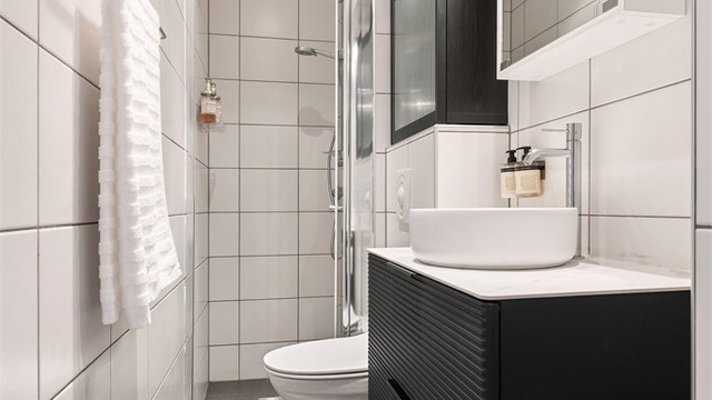 Badet har et praktisk dusjhjørne med innfellbare glassdører.
