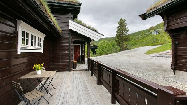 Overbygget inngangsparti og svalgang som leder langs hytta.