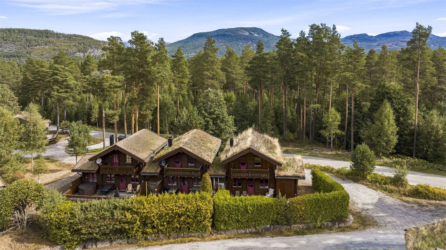 Eiendommen ligger fint til i terrenget, omgitt av skog og fjell.