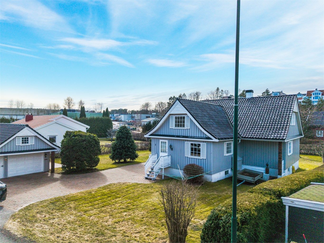 Eiendommen ligger på en flat tomt med plen og hekk.