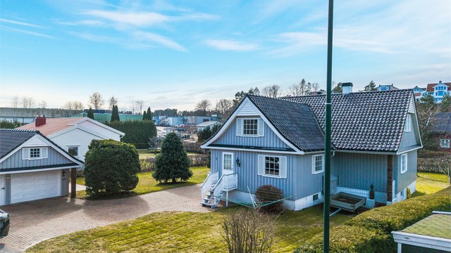 Eiendommen ligger på en flat tomt med plen og hekk.