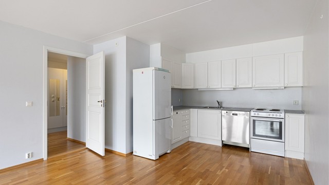 Moderne løsning med åpen kjøkkenløsning. Kjøkkeninnredning fra byggeår med profilerte hvite fronter.