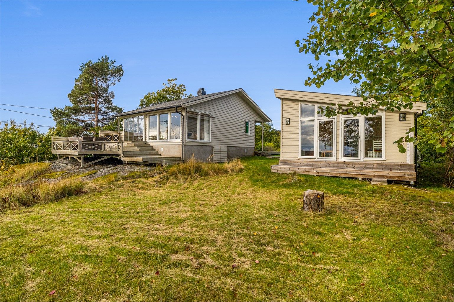 Tomten er naturskjønn med gressplen og svaberg.
