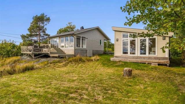 Tomten er naturskjønn med gressplen og svaberg.