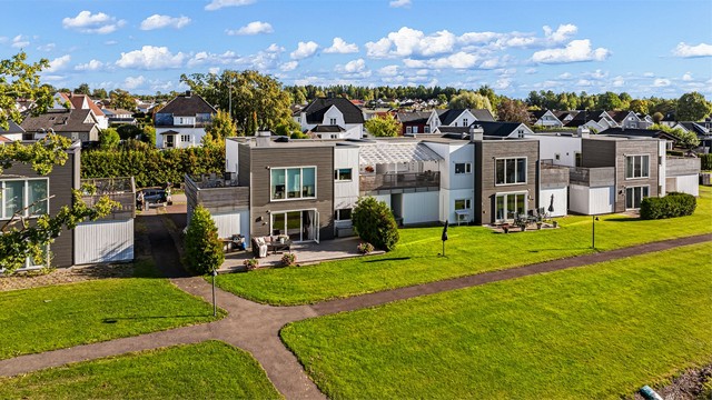 Bak boligen er det et romslig, felles plenareal med asfaltert gangvei.