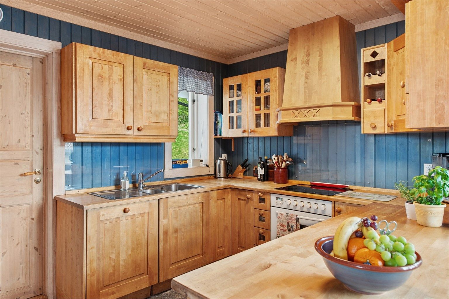 Heltre kjøkkeninnredning med profilerte fronter, nedfelt oppvaskkum og integrert stekeovn og platetopp.