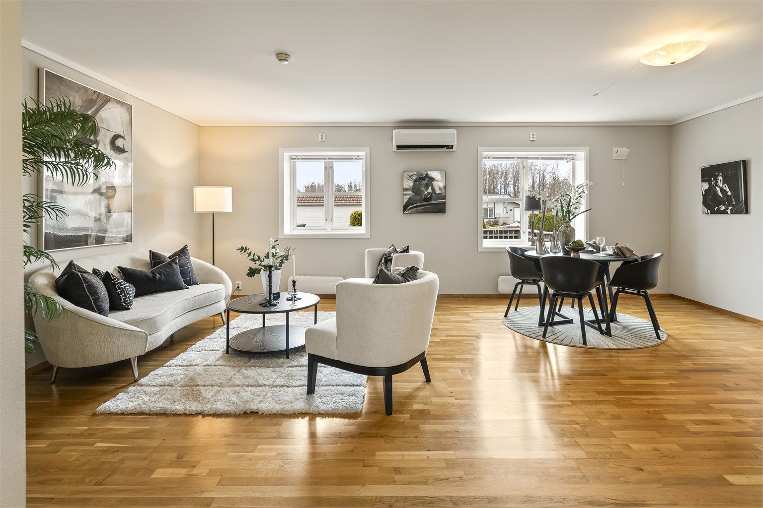 En lys og lettmøblert stue med gjennomgående parkett og god plass til både sofagruppe og spisebord.