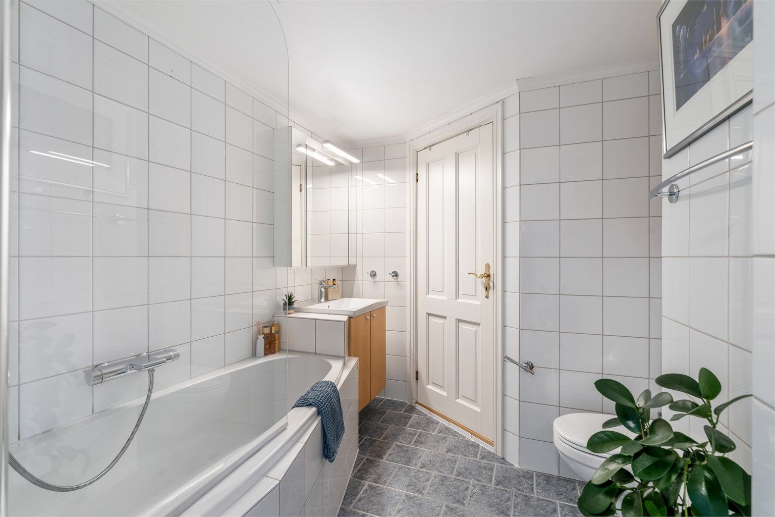 Badet er utstyrt med varmekabler i gulv, vegghengt servant og toalett og badekar.
