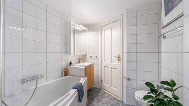Badet er utstyrt med varmekabler i gulv, vegghengt servant og toalett og badekar.