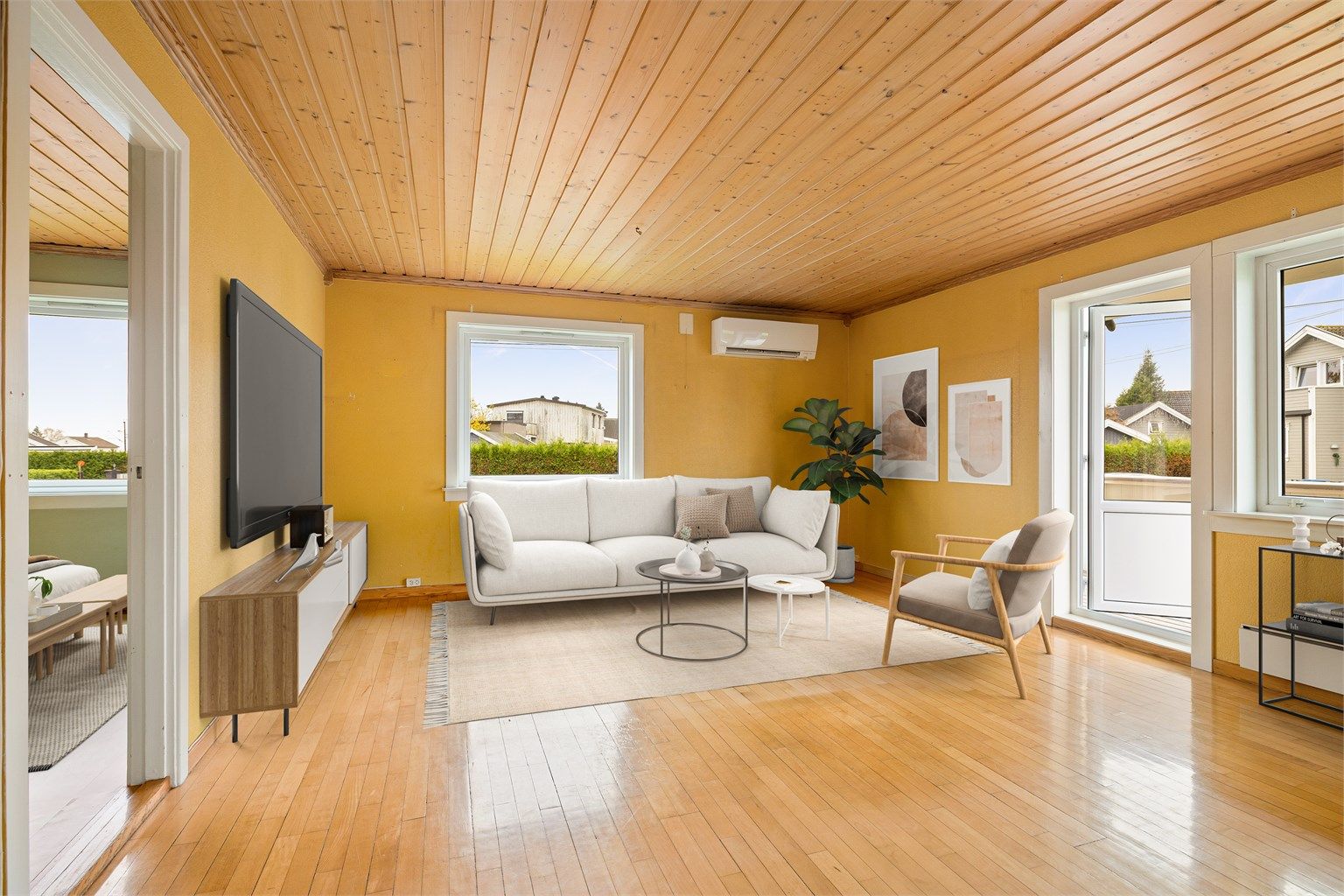 Lys stue med varme treelementer, store vinduer som slipper inn rikelig dagslys. Bildet er digitalstylet.