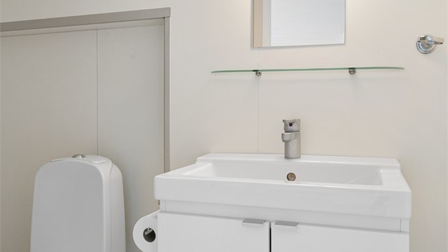 Badet i loftsleiligheten har gulvbelegg, våtromsplater på veggene og vegghengt servantskap.