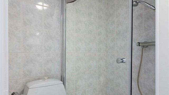 Badet har flislagt gulv med gulvvarme og dusjhjørne. Badet har et oppgraderingsbehov.