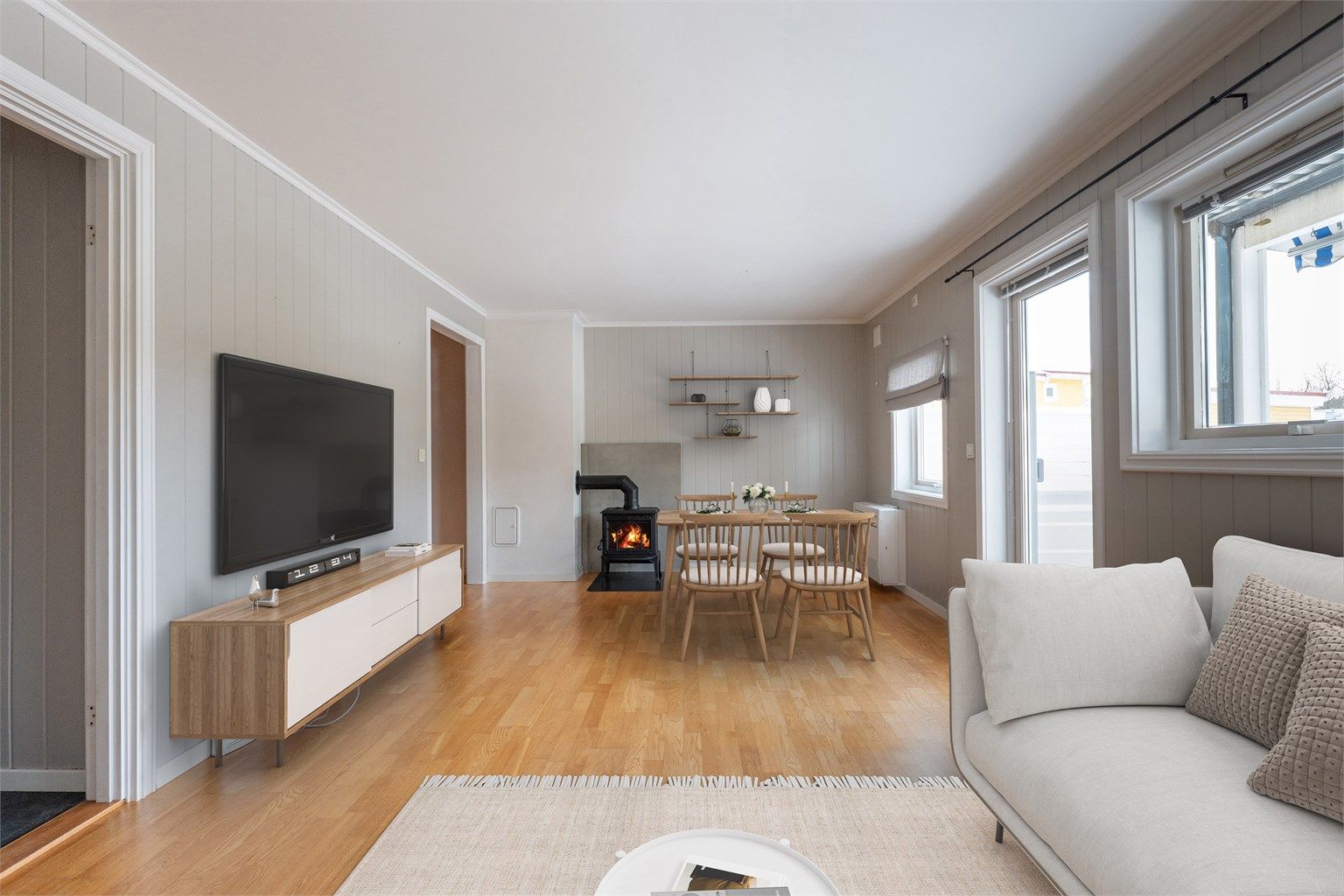 I stuen er både vedovn og varmepumpe nylig installert. Det er i tillegg elektrisk gulvvarme her og på kjøkkenet, termostat er skiftet ut i 2026. Bildet er digitalt møblert.