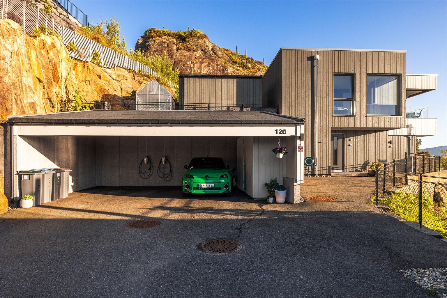 Her kjører du til endes og parkerer i carporten. To elbil ladere medfølger. Carporten hadde opprinnelig plass til tre biler, men etter innvendig bod ble bygget er det plass til 2,5 biler.