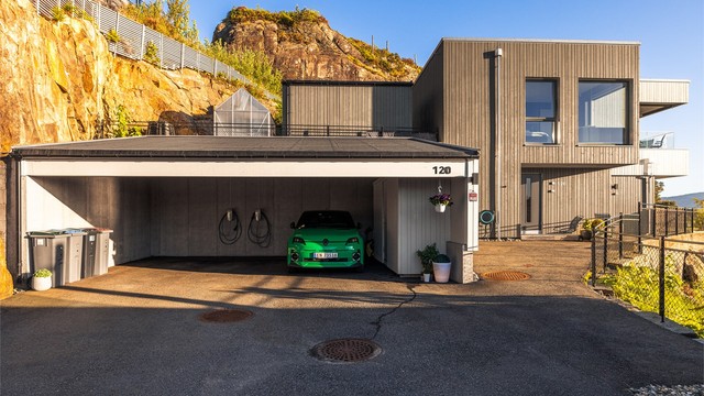 Her kjører du til endes og parkerer i carporten. To elbil ladere medfølger. Carporten hadde opprinnelig plass til tre biler, men etter innvendig bod ble bygget er det plass til 2,5 biler.