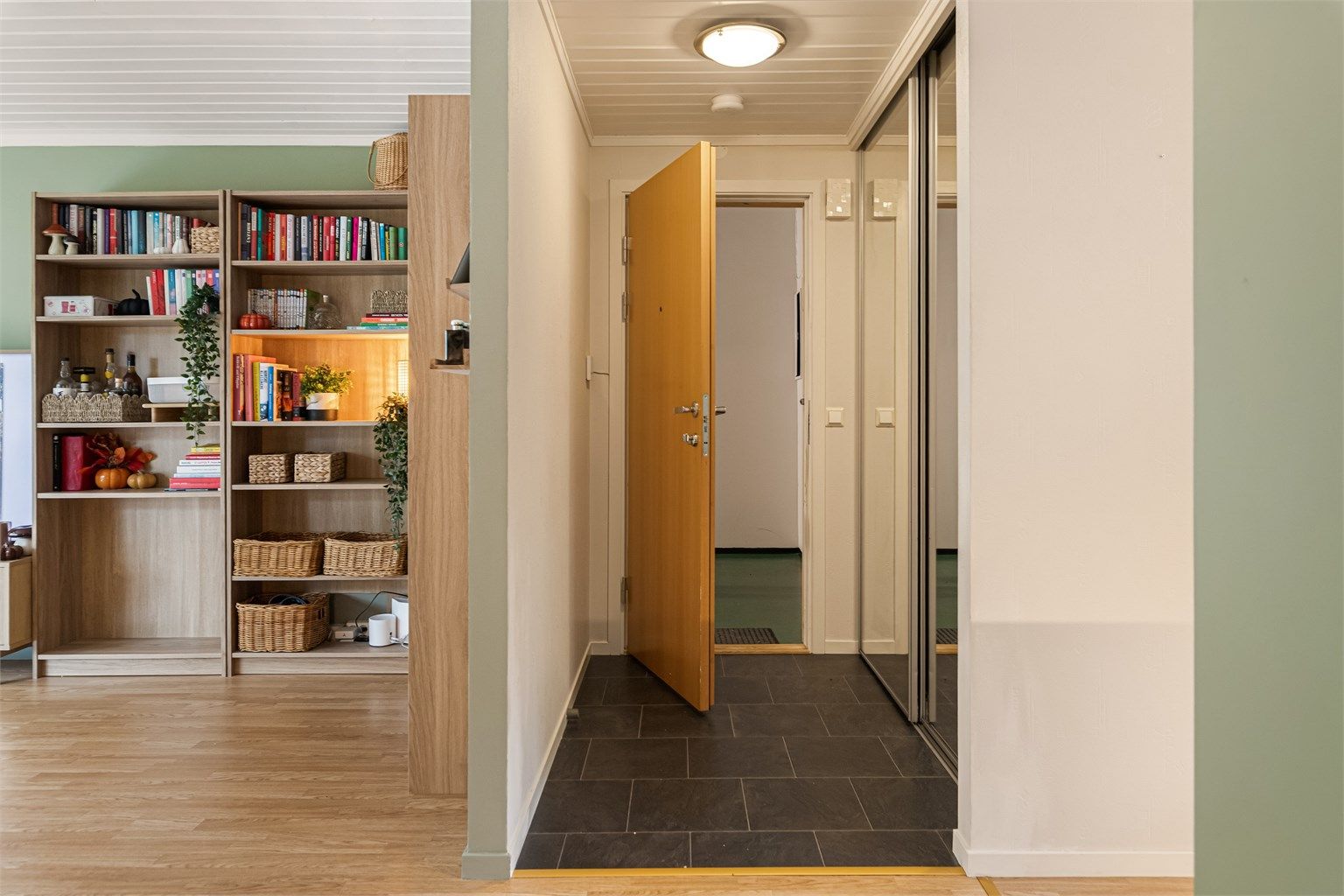 Entreen er innredet med flislagt gulv og romslig skyvedørsgarderobe med speilfronter.