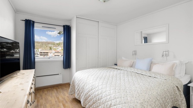 Hovedsoverommet har plassbygget garderobeskap med skyvedører og utsikt mot havnen.
