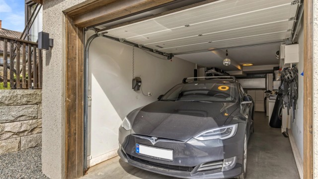 Garasje for en bil intregrert i bygningskroppen. Det er montert lader i garasjen
