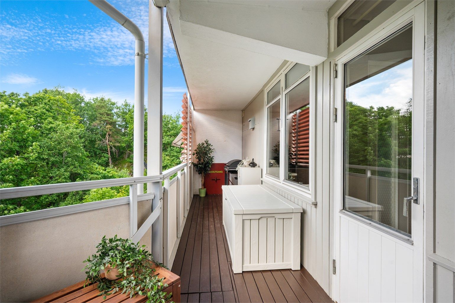 Verandaen strekker seg langs leilighetens fasade og har gulv belagt med terrassebord.