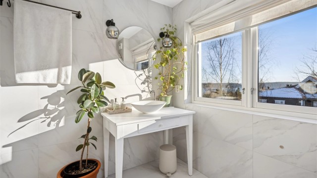 Badet er innredet med kombinert veggmontert og gulvstående innredning med ovenpåliggende servant og ettgreps armatur og speil med integrert belysning.