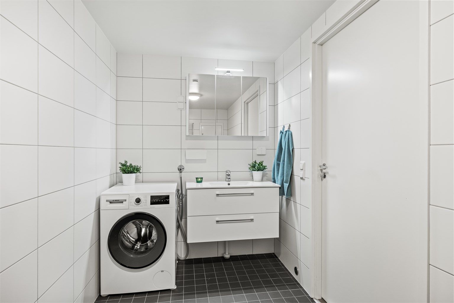 Her er det servantinnredning, speilskap med belysning og opplegg for vaskemaskin.