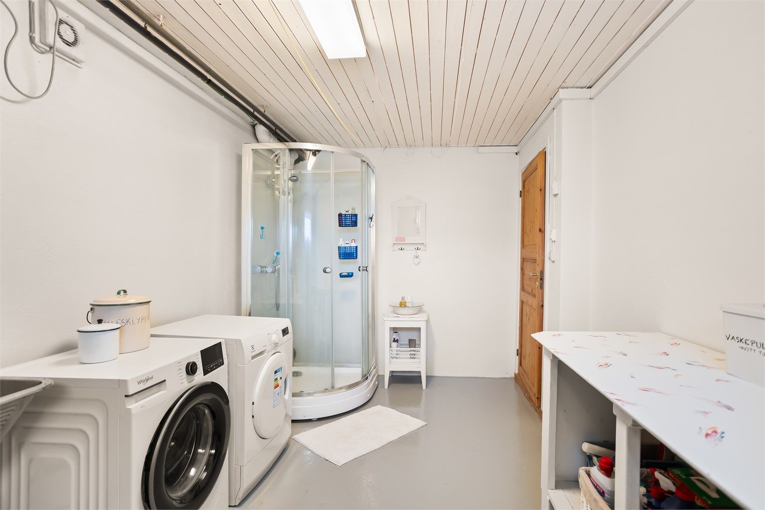 Praktisk vaskerom med elektrisk gulvvarme, dusjkabinett og opplegg for vaskemaskin og tørketrommel.