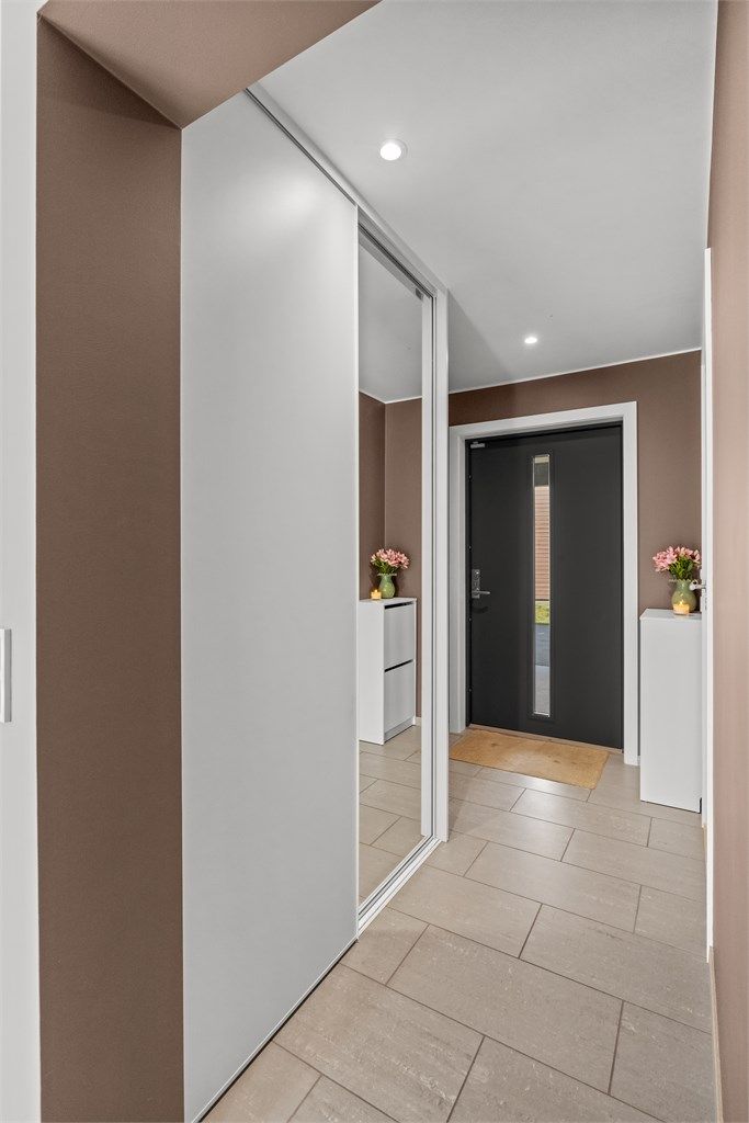 God plass til oppbevaring av yttertøy i en romslig skyvedørsgarderobe.