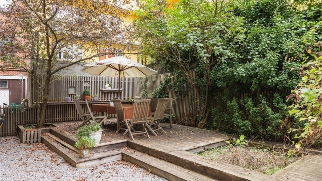 Avskjermet bakgård med beplantning, grusede arealer og terrasseplatting i trykkimpregnert virke.