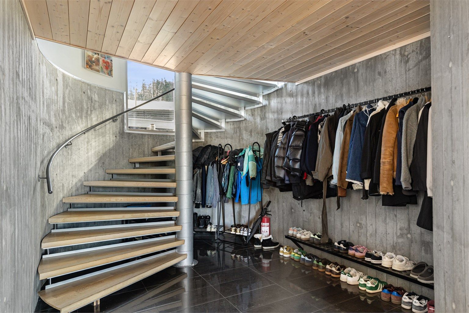 Inngangspartiet i kjelleren har en tøff kombinasjon av fliser på gulv og vegger i ubehandlet betong.